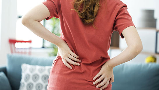 Woman holding lower back in pain before visiting Sandpoint chiropractor